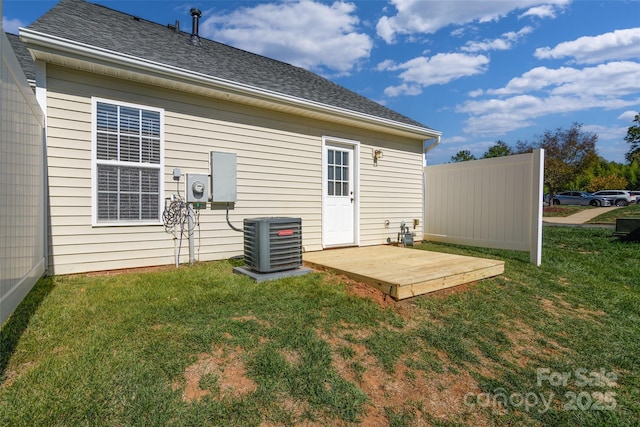 back of property with central AC and a yard