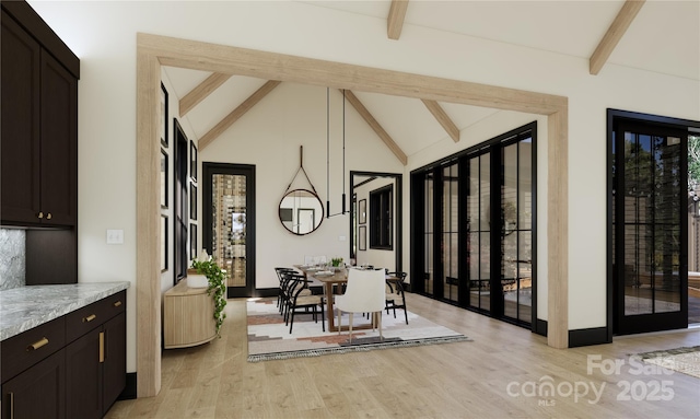 dining area featuring light wood-type flooring and vaulted ceiling with beams