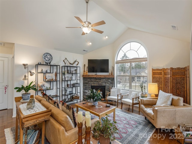 living room featuring vaulted ceiling, ceiling fan, a fireplace, and wood-type flooring