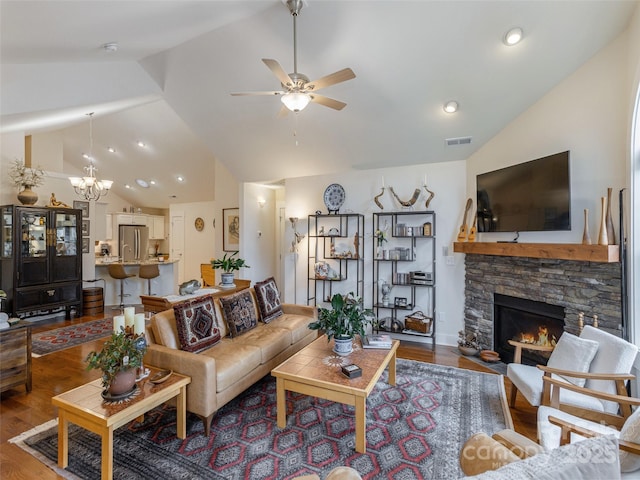 living room featuring a fireplace, dark wood-type flooring, ceiling fan with notable chandelier, and vaulted ceiling