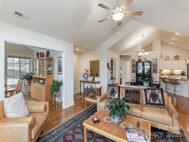 living room featuring vaulted ceiling, ceiling fan with notable chandelier, and dark hardwood / wood-style floors