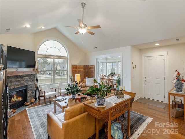 living room with a wealth of natural light, a fireplace, and wood-type flooring