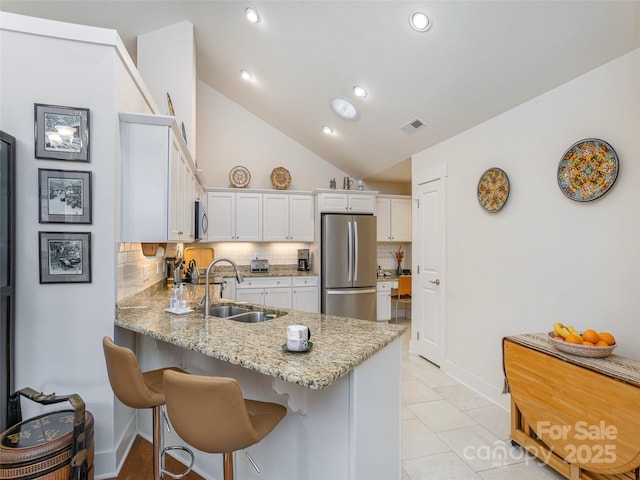 kitchen featuring decorative backsplash, white cabinets, sink, stainless steel appliances, and light tile patterned flooring