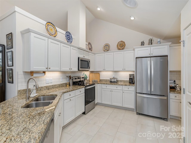 kitchen featuring light stone countertops, appliances with stainless steel finishes, white cabinetry, sink, and high vaulted ceiling