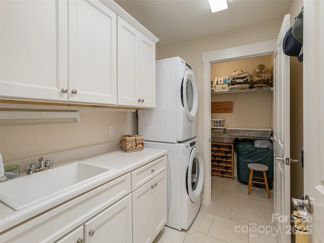 clothes washing area featuring stacked washer / dryer, light tile patterned flooring, sink, and cabinets