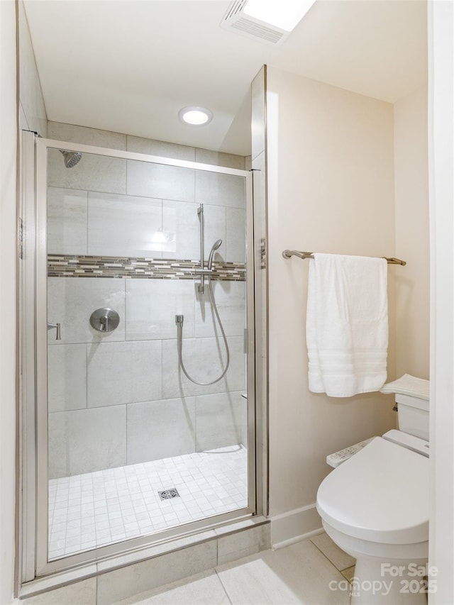 bathroom featuring toilet, a shower with shower door, and tile patterned flooring