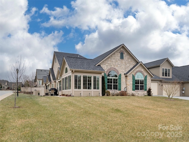 view of front facade featuring a garage, a front yard, and a sunroom