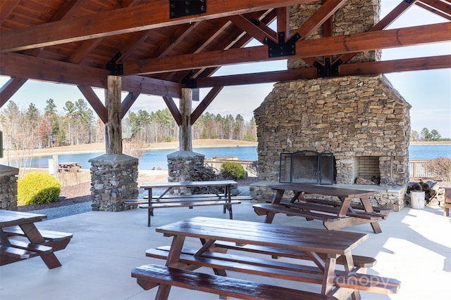 view of patio with a gazebo, an outdoor stone fireplace, and a water view