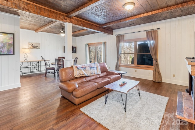 living room with dark wood-type flooring, ceiling fan, beam ceiling, a brick fireplace, and wooden ceiling