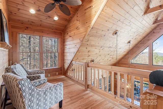 living area featuring lofted ceiling, wood ceiling, ceiling fan, hardwood / wood-style floors, and wood walls