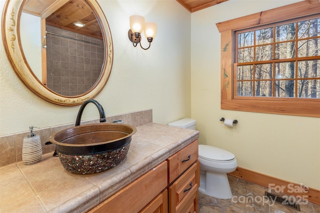 bathroom featuring toilet, vanity, and walk in shower