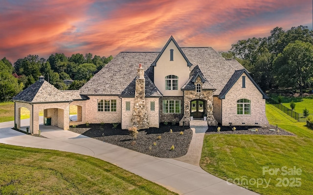 french country style house featuring a carport, a lawn, and french doors