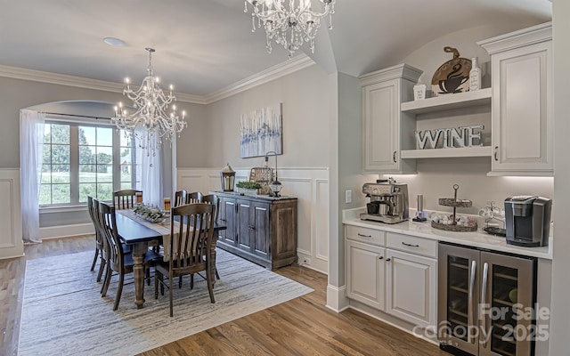 dining space featuring dark hardwood / wood-style flooring, ornamental molding, beverage cooler, and a chandelier