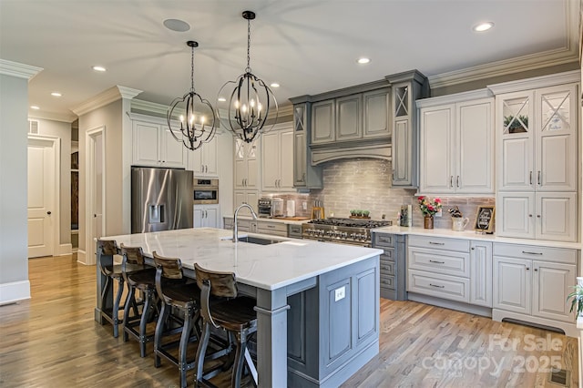 kitchen with appliances with stainless steel finishes, sink, backsplash, hanging light fixtures, and a center island with sink