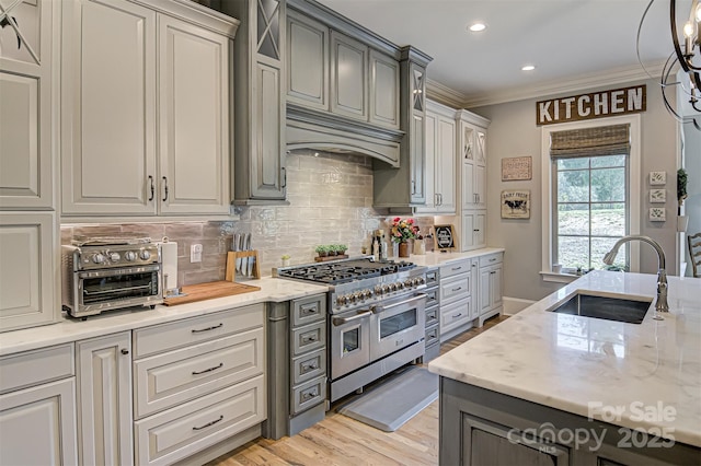 kitchen featuring sink, gray cabinets, premium range hood, and range with two ovens