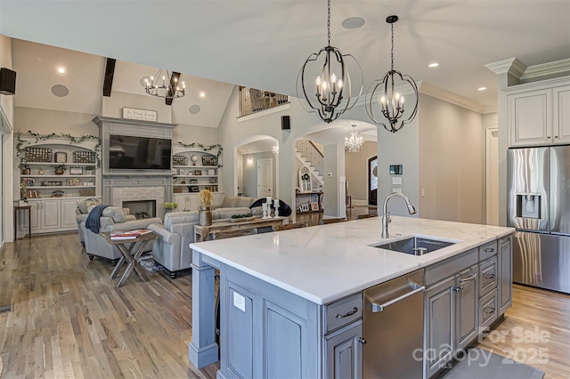 kitchen featuring sink, a kitchen island with sink, white cabinetry, stainless steel appliances, and a stone fireplace