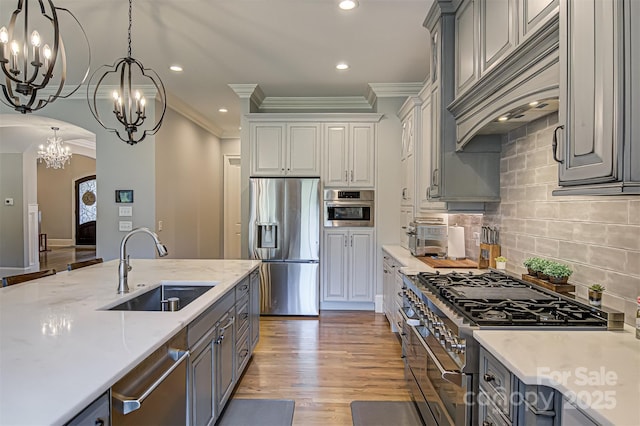 kitchen with sink, appliances with stainless steel finishes, gray cabinetry, backsplash, and custom exhaust hood