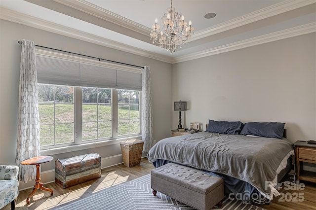 bedroom with an inviting chandelier, light hardwood / wood-style flooring, ornamental molding, and a raised ceiling