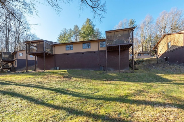 rear view of property featuring a yard and a sunroom