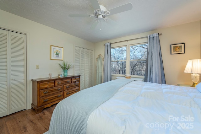 bedroom with hardwood / wood-style flooring, ceiling fan, a textured ceiling, and two closets