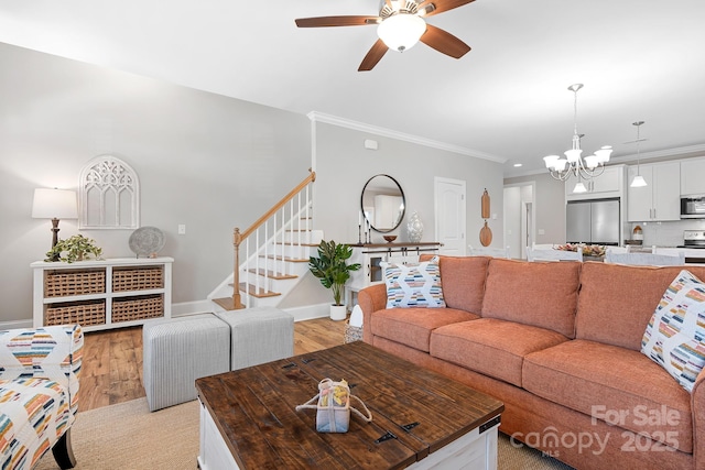 living room with crown molding, ceiling fan with notable chandelier, and light hardwood / wood-style floors