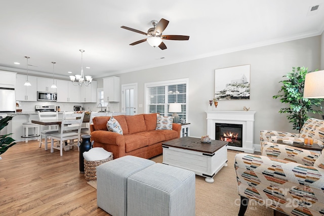 living room with ornamental molding, ceiling fan with notable chandelier, and light wood-type flooring