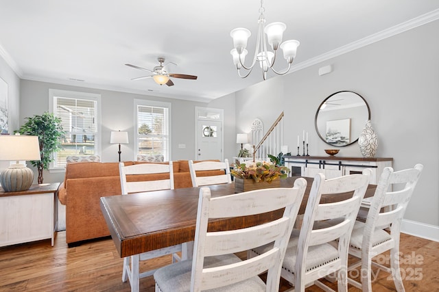 dining area featuring ornamental molding, ceiling fan with notable chandelier, and light wood-type flooring