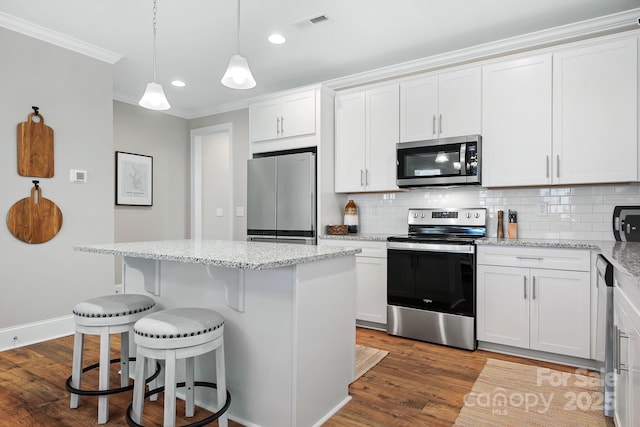 kitchen with light stone countertops, stainless steel appliances, white cabinets, and a kitchen island