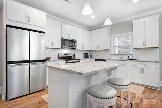 kitchen with white cabinetry, pendant lighting, light stone countertops, and appliances with stainless steel finishes