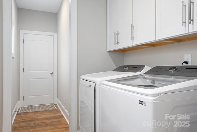 laundry area with cabinets, wood-type flooring, and washing machine and clothes dryer