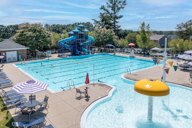 view of pool with a playground, a water slide, and a patio area