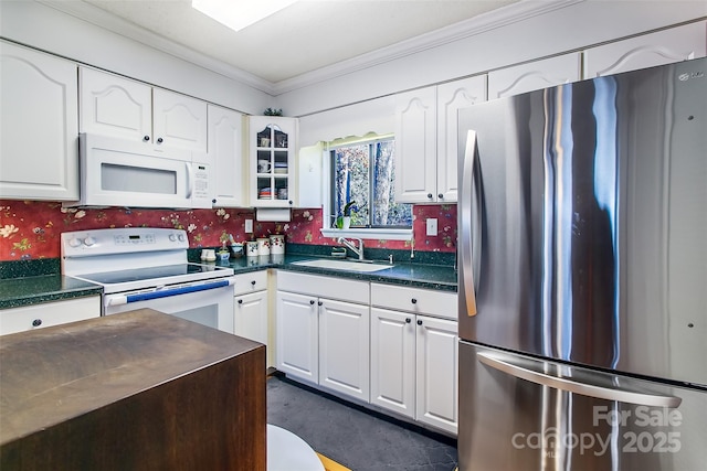 kitchen with white appliances, dark countertops, a sink, and white cabinets