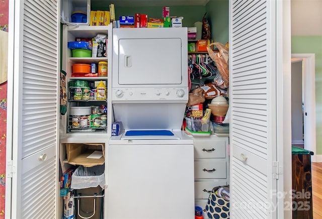 clothes washing area with stacked washing maching and dryer and laundry area