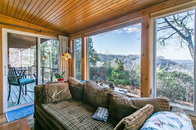 sunroom / solarium featuring wood ceiling, a forest view, and a wealth of natural light