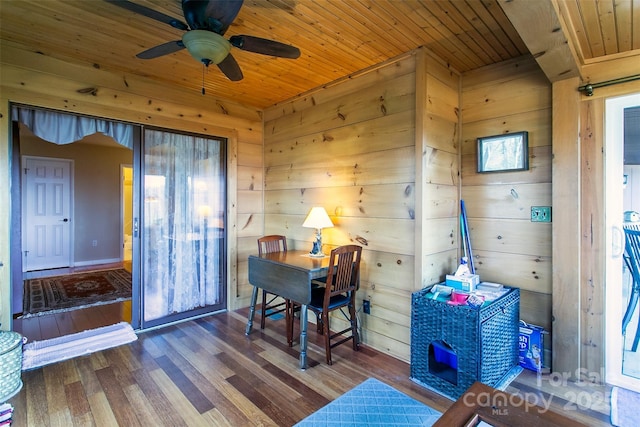 office space featuring a ceiling fan, wood ceiling, wood walls, and dark wood-style flooring