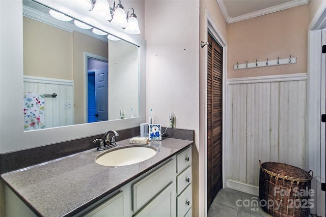 bathroom featuring a wainscoted wall, vanity, a closet, tile patterned floors, and crown molding