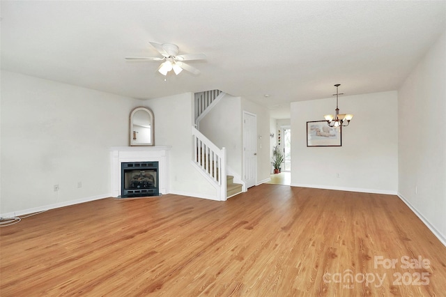 unfurnished living room featuring ceiling fan with notable chandelier and light hardwood / wood-style floors