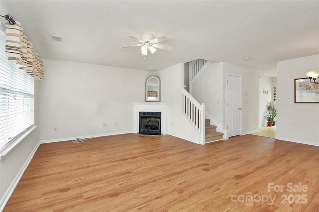 unfurnished living room featuring ceiling fan, a textured ceiling, and light wood-type flooring