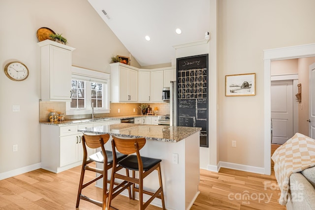 kitchen featuring white cabinetry, stone countertops, a center island, and a breakfast bar area