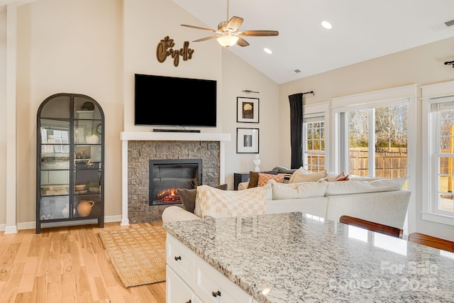 kitchen with white cabinetry, a stone fireplace, light stone counters, and a wealth of natural light