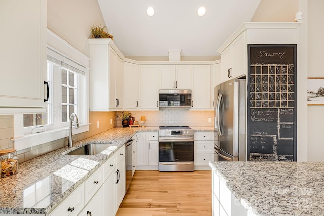 kitchen featuring stainless steel appliances, light stone countertops, sink, and light hardwood / wood-style flooring