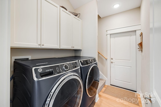 laundry area with hardwood / wood-style floors, washing machine and dryer, and cabinets