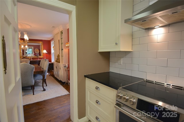 kitchen with dark wood-style floors, stainless steel electric stove, dark countertops, decorative backsplash, and extractor fan