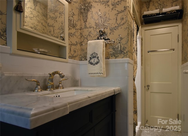 bathroom featuring tile walls, wainscoting, vanity, and wallpapered walls