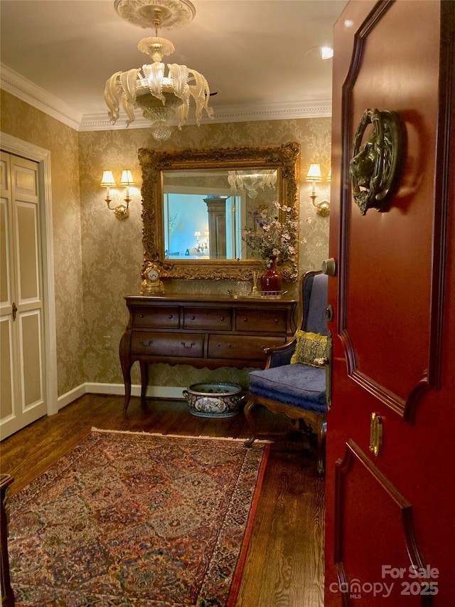 sitting room with ornamental molding, wallpapered walls, a notable chandelier, and wood finished floors