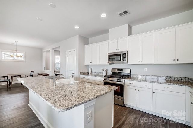 kitchen with stainless steel appliances, an island with sink, and white cabinets