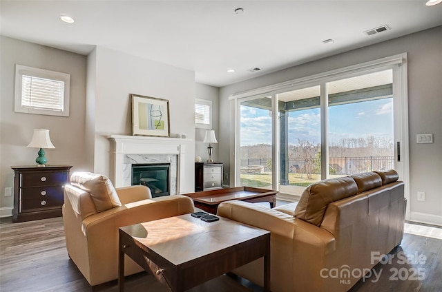 living room with a high end fireplace, a wealth of natural light, and light wood-type flooring