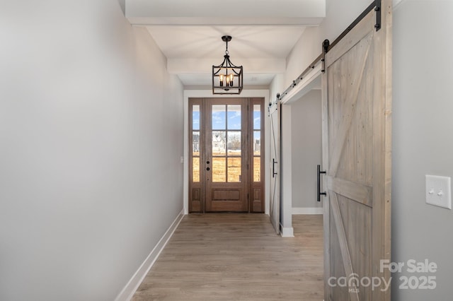 doorway to outside featuring a notable chandelier, a barn door, and light wood-type flooring