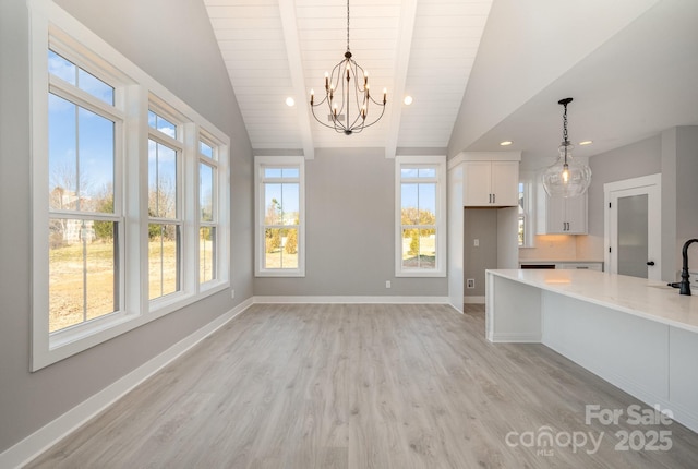 kitchen featuring a wealth of natural light, decorative light fixtures, lofted ceiling with beams, white cabinets, and light hardwood / wood-style flooring