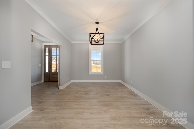 interior space featuring light hardwood / wood-style flooring, ornamental molding, and a chandelier